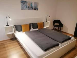 a white bed with two lamps and a chair at Ferienwohnung Hildegard Eiter in Sankt Leonhard im Pitztal