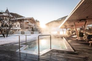 una bañera de hidromasaje en la nieve junto a una casa en Hotel Sonnegg, en Saalbach Hinterglemm