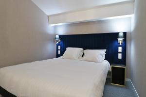 a bedroom with a large white bed with a blue headboard at Hôtel Napoléon in La Turbie