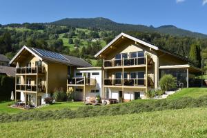 a house on a hill with mountains in the background at Appartments Urmonti in Schruns