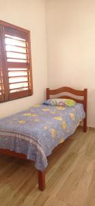 a bedroom with a bed with a blue comforter and a window at Casa Tropicana in Flecheiras