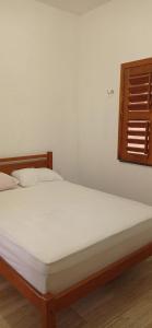a bedroom with a bed with white sheets and a window at Casa Tropicana in Flecheiras