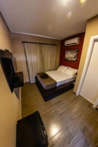 um pequeno quarto com uma cama e uma televisão em Bonabrigo Hostel & Suítes em Balneário Camboriú
