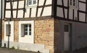 ein Backsteingebäude mit einer weißen Tür und einem Fenster in der Unterkunft petit studio pour une personne à Lobsann in Lobsann