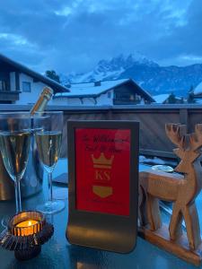 een bord op een tafel met wijnglazen en een hert bij KS - Suiten in Sankt Johann in Tirol