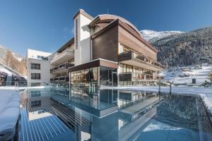 ゼルデンにあるBergland Design- und Wellnesshotelの雪中スイミングプール付きの建物