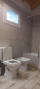 een badkamer met een toilet, een wastafel en een bad bij Cabañas Boutique Los Cipreses in Villa Ventana
