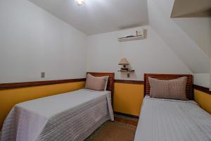 two beds in a room with yellow and white walls at Mirágua Refugios Pousada in Brotas +45 photos