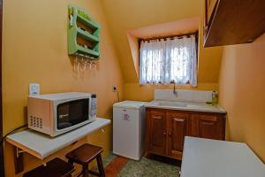 a small kitchen with a microwave and a refrigerator at Mirágua Refugios Pousada in Brotas
