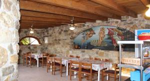 a restaurant with tables and chairs in a stone wall at ANEMOMYLOS Lefkimmi LUXUS SUITES-BOUTIQUE HOTEL & POOL in Lefkímmi