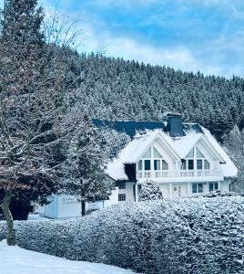een huis bedekt met sneeuw op een heuvel bij Landhaus Mühlenberg in Willingen
