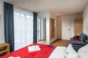 Falcon Suites Zell am See في زيل أم سي: غرفة نوم بسرير واريكة