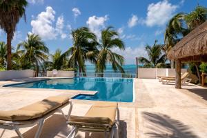 a swimming pool with palm trees and the ocean at Casa Bonita and villas in Isla Mujeres