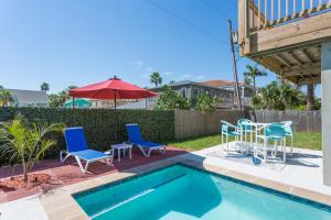 um quintal com uma piscina com cadeiras e uma mesa em House of Neptune Steps from the sea and private pool em South Padre Island