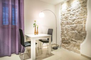 comedor con mesa blanca y sillas negras en Split Oasis Studio Apartments, en Split