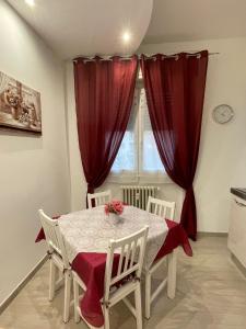 uma sala de jantar com uma mesa com cortinas vermelhas em Alice sweet home em Corsico