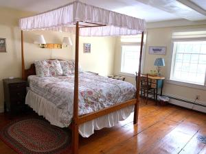 ein Schlafzimmer mit einem Himmelbett und Holzboden in der Unterkunft Franklyn Farm Inn in Chester