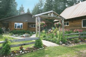 Athol的住宿－Cedar Mountain Farm Bed and Breakfast LLC，一座带围栏和鲜花的木屋