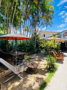 un patio con mesa, sillas y sombrilla en Tombo Beach Hostel & Pousada, en Guarujá