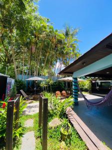 um alpendre com uma rede de descanso, cadeiras e árvores em Tombo Beach Hostel & Pousada no Guarujá