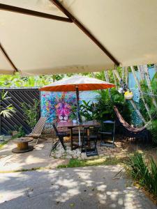 un patio con mesa, sillas y sombrilla en Tombo Beach Hostel & Pousada en Guarujá