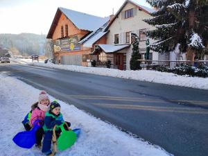 two children playing in the snow on a road at Penzion U Zastávky in Rokytnice nad Jizerou