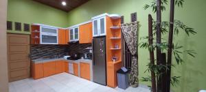 a kitchen with orange and green walls at House of Runsia Guesthouse in Pagaralam