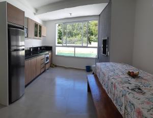 a kitchen with a bed and a large window at Apartamento 103 novo 100 mts da Praia Espanha Residence in Florianópolis