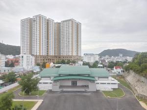 a building with a green roof in front of tall buildings at Thanh Nien Hotel - Vung Tau in Vung Tau