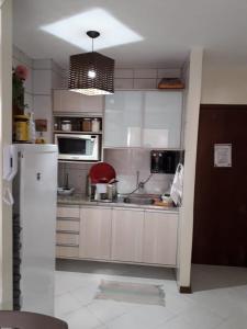 een keuken met witte kasten en een witte koelkast bij Duplex em Praia do Forte a 50m da vila in Mata de Sao Joao
