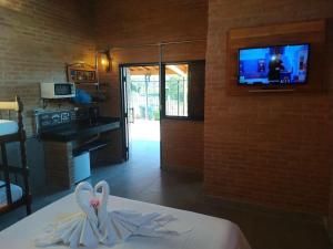a room with a bed and a tv on a wall at La Villa Chalés in Serra Negra