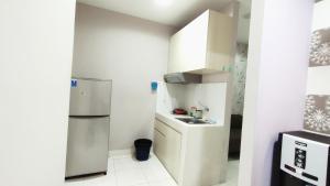 a small kitchen with a refrigerator and a sink at Kozy Room Sentul Tower Apartemen in Bogor