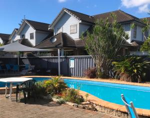 a house with a swimming pool in front of a house at Avlon Gardens Motel in Ballina