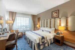 um quarto de hotel com uma cama grande e uma secretária em Grand Al Safi Hotel em Medina