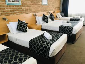 a group of four beds in a room at Jumbuck Motor Inn in Tenterfield