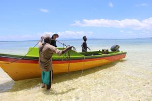 a group of men standing on a boat on the beach at Evis Resort at Nggatirana Island in Halisi