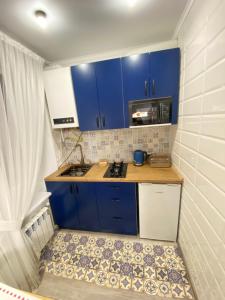 a small kitchen with blue cabinets and a sink at Люкс апартаменти «Д.І.М.» in Kamianets-Podilskyi