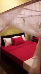 1 dormitorio con 1 cama con almohadas rojas y blancas en Sawanga Home Stay, en Weligama