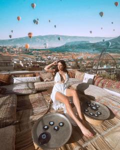 a woman in a white dress sitting on a couch with hot air balloons at Caravanserai Inn Hotel in Goreme