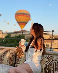 a woman sitting on a couch with a cup of coffee at Caravanserai Inn Hotel in Göreme