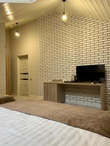 een slaapkamer met een tv en een bakstenen muur bij Max Spa Hotel in Nevinnomyssk