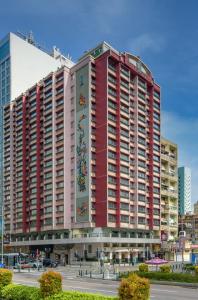 een groot rood-wit gebouw met een kraan bij Hotel Sintra in Macau