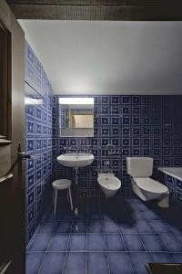 a blue tiled bathroom with a sink and a toilet at Chesa Murtiroel - Samedan in Samedan