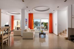 a living room with orange curtains and a couch and a table at Villa Kivotos in Lardos