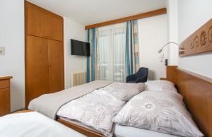 1 dormitorio con 1 cama, 1 silla y 1 ventana en Appartementhaus Franz Samonig, en Drobollach am Faakersee