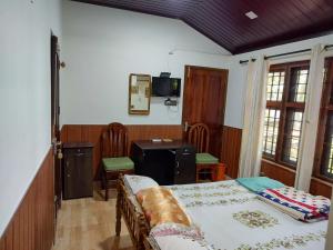 1 dormitorio con cama, mesa y escritorio en West Wind Homez - Home Stay, en Kochi