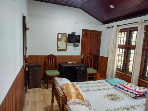 a bedroom with a bed and a table and a desk at West Wind Homez - Home Stay in Cochin