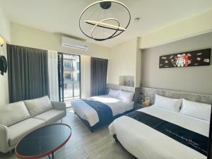 um quarto de hotel com duas camas e um sofá em Six Seasons Inn - Qian He em Anping