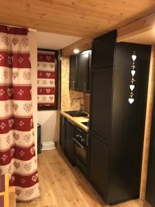 a kitchen with black cabinets and a refrigerator at La Grande Ourse - 4 pièces, 6 personnes in Méribel