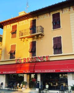 um hotel com um toldo vermelho num edifício em Hotel La Regence em Villefranche-sur-Mer